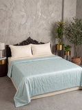 Mint green all season comforter with tufted dot detailing on bed with cream pillows